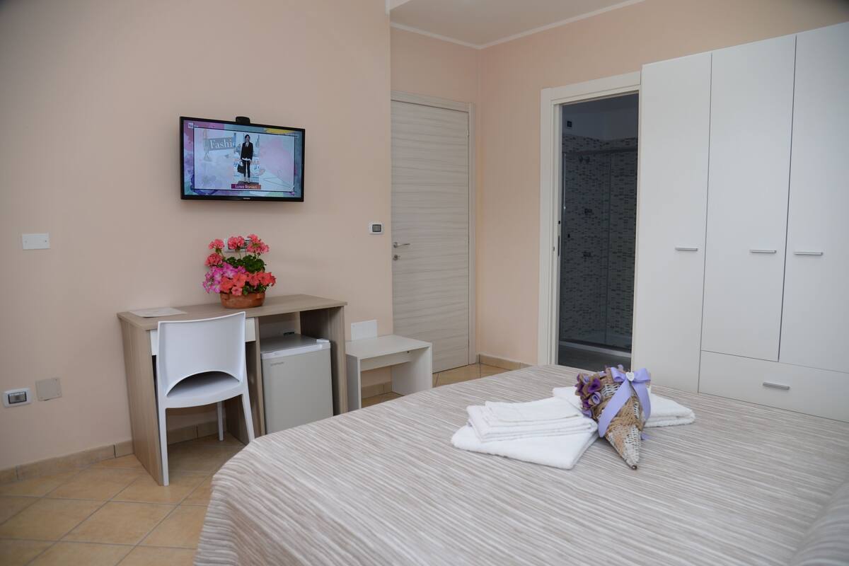 Ein Hotelzimmer mit Bett, Schreibtisch, Stuhl, Fernseher und Kleiderschrank.