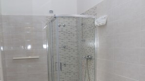 Un bagno moderno con doccia vetrata, un bidet e un lavandino.