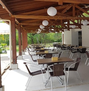 A covered outdoor dining area with tables and chairs, wooden beams, and hanging paper lanterns. - Hotel Peñon Suites (Girardot)