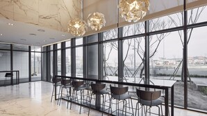 A modern interior with a marble floor, large windows, and a seating area with chairs and tables. - Ramada Encore by Wyndham Gimpo Han River Hotel (Gimpo)