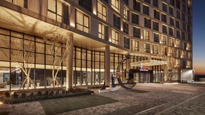 A modern hotel with a large entrance, a covered walkway, and a landscaped area with trees and shrubs. - Ramada Encore by Wyndham Gimpo Han River Hotel (Gimpo)