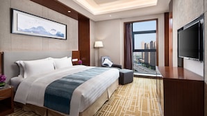 A modern hotel room with a large bed, a flat-screen TV, a desk, and a view of the city. - Ramada by Wyndham Wuhan Hanyang (Wuhan)