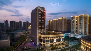 A high-rise hotel with a modern design, featuring a prominent entrance and a large digital billboard. - Ramada by Wyndham Wuhan Hanyang (Wuhan)