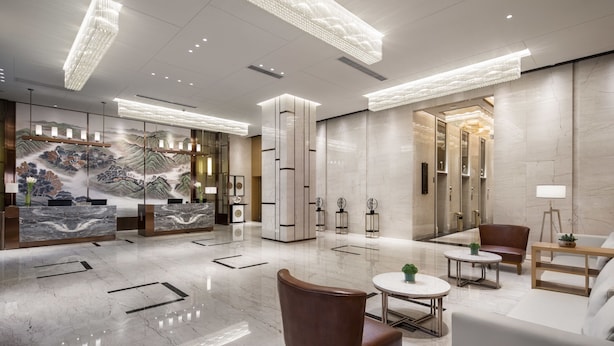 A modern lobby with a marble floor, a reception desk, seating area, and a mural. - Ramada by Wyndham Wuhan Hanyang (Wuhan)