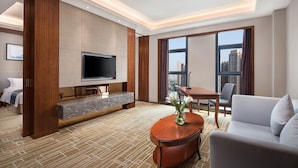 A modern hotel room with a large TV, a dining area, and a sofa. - Ramada by Wyndham Wuhan Hanyang (Wuhan)