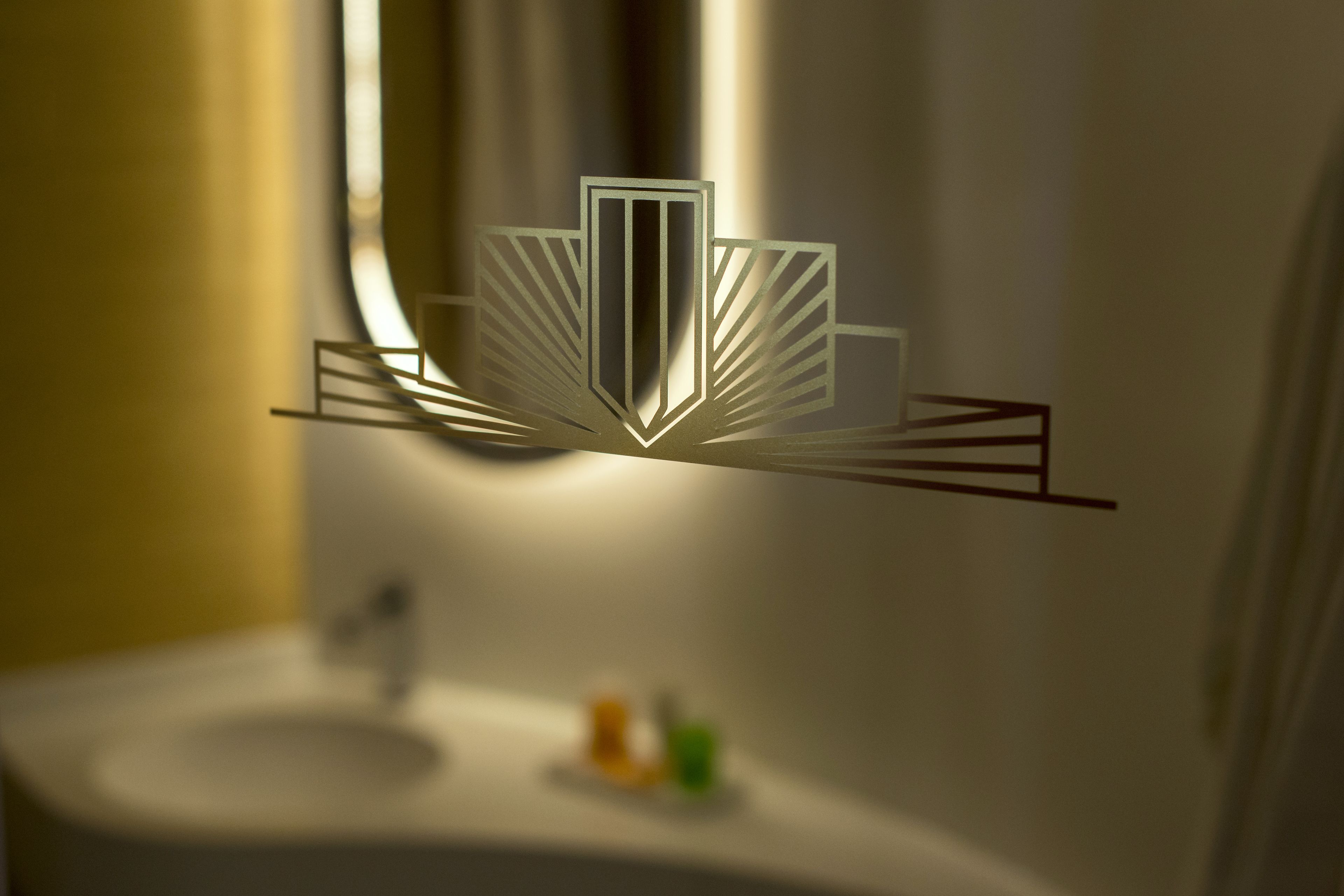 A modern bathroom with a minimalist design, featuring a central geometric light fixture and a white sink.