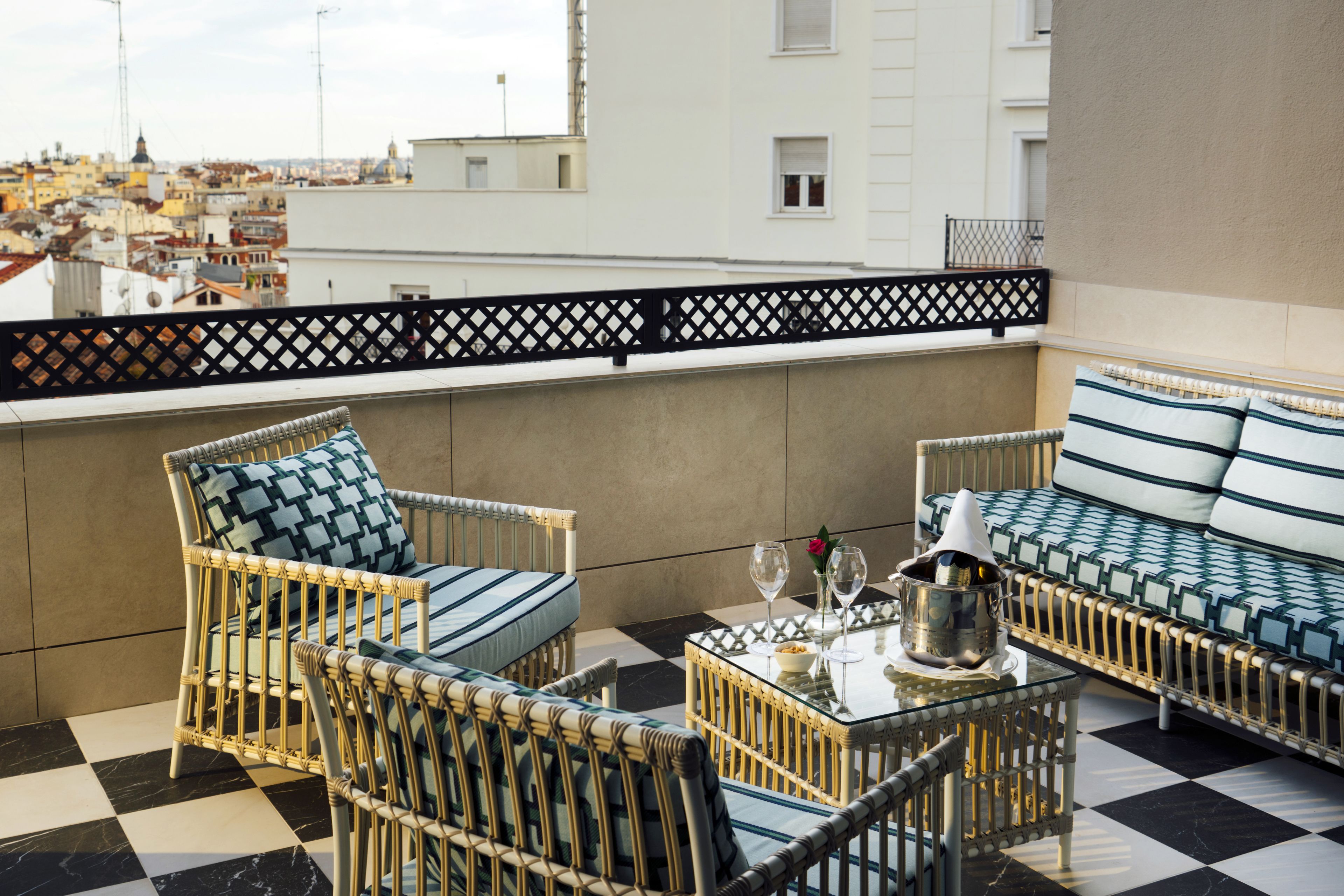 Un balcon doté de meubles en osier, d’un sol à carreaux et offrant une vue sur la ville.