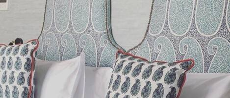 A bed with a patterned headboard and decorative wall sconces.