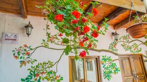 A room with a large window, wooden beams, and a hanging flower pot. - Tucan Hostel (Cusco)