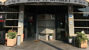 The exterior of HOTEL REPUBBLICA with multiple flags, including the Italian flag, and a sign indicating the hotel's name. - HR Hotel (Monfalcone)