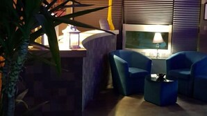 A dimly lit room with a bed, a nightstand, a lamp, and a potted plant. - HR Hotel (Monfalcone)