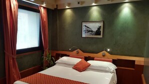 A hotel room with a large bed, a wooden headboard, a framed picture on the wall, and a window with curtains. - HR Hotel (Monfalcone)