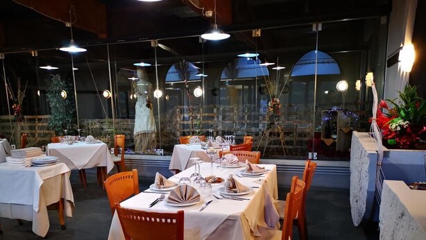 A restaurant with tables set for dining, chairs, and hanging lights. - HR Hotel (Monfalcone)