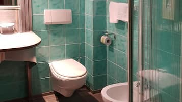 A bathroom with a toilet, a sink, and a glass-enclosed shower area.
