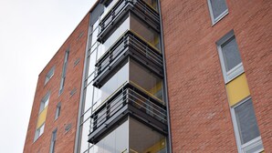 A multi-story building with a modern architectural design, featuring a combination of brick and glass facades, and multiple balconies. - DP Apartments Vaasa (Vaasa)