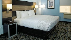 A hotel room with a bed, bedside lamps, a nightstand with a phone, and a framed picture on the wall.