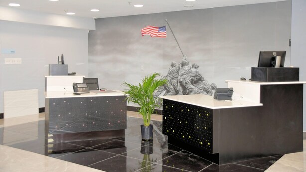 A reception area with a flag, a statue, and a plant.