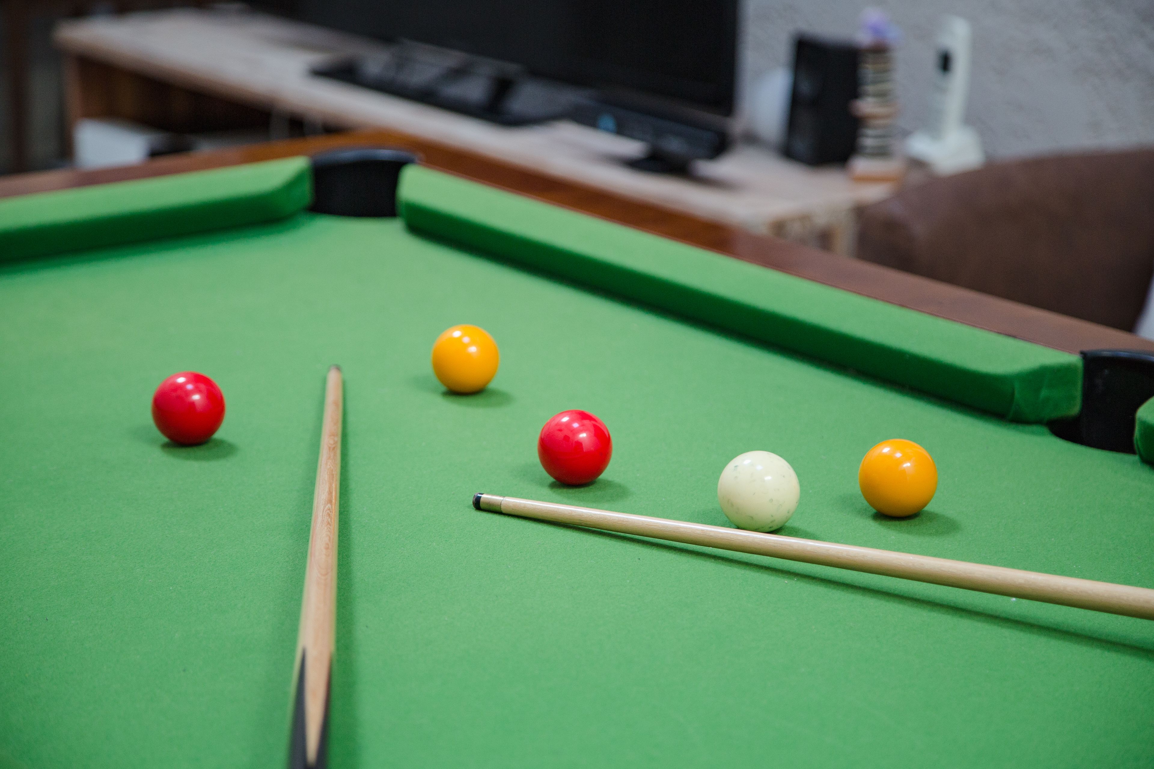 A pool table with balls and a cue stick.