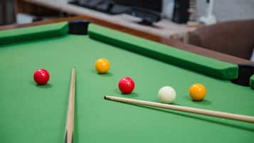 A pool table with balls and a cue stick.