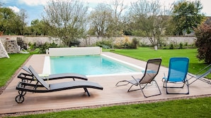 A rectangular swimming pool with a wooden deck and lounge chairs. - Au Caprice de L'Atre (Tonnoy)