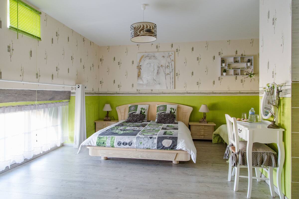Un dormitorio con cama, mesitas de noche, escritorio y una silla.