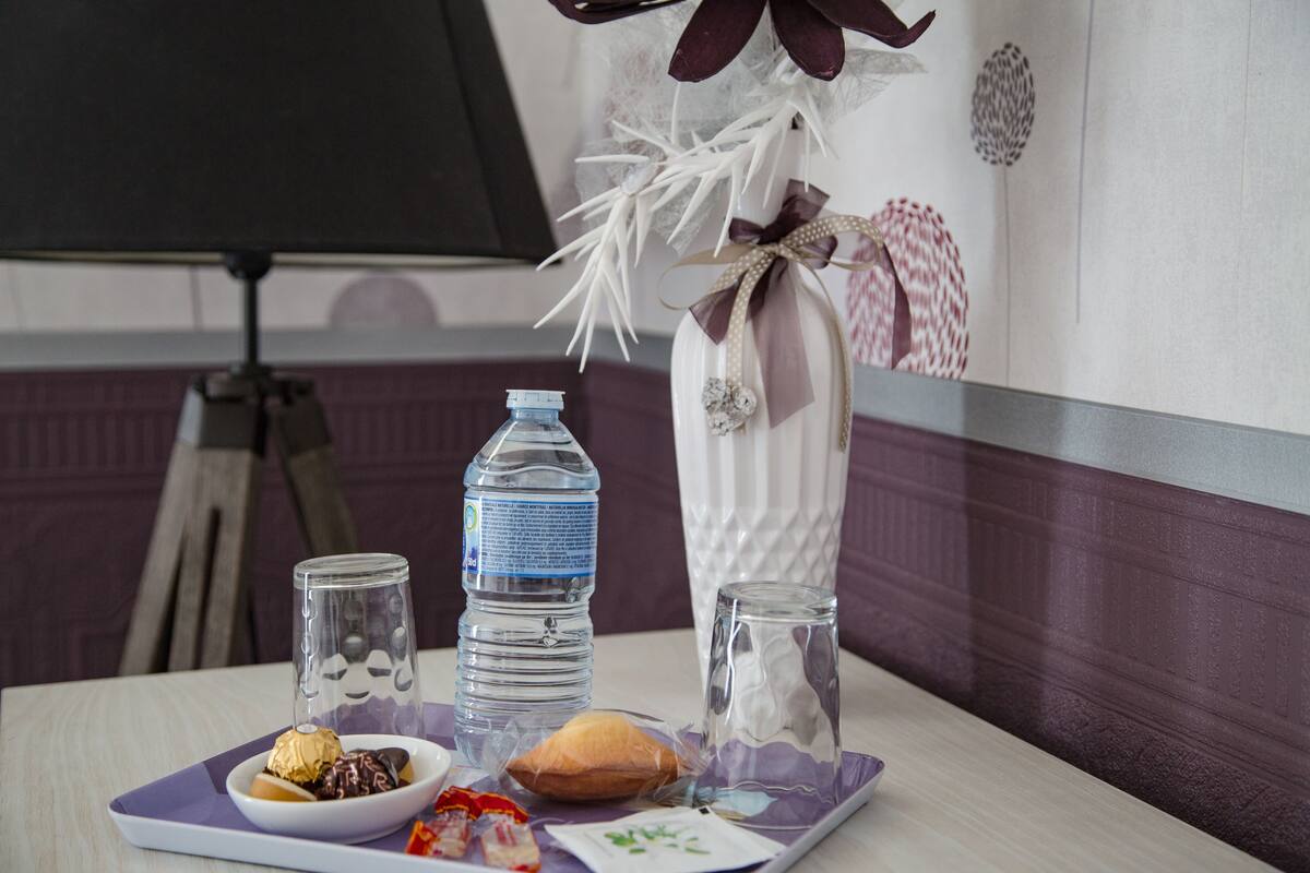 Una mesa con una botella de agua, un vaso, un recipiente pequeño con comida y un adorno.