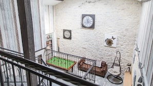 A room with a billiards table, a rocking chair, and a stone wall with clocks. - Au Caprice de L'Atre (Tonnoy)
