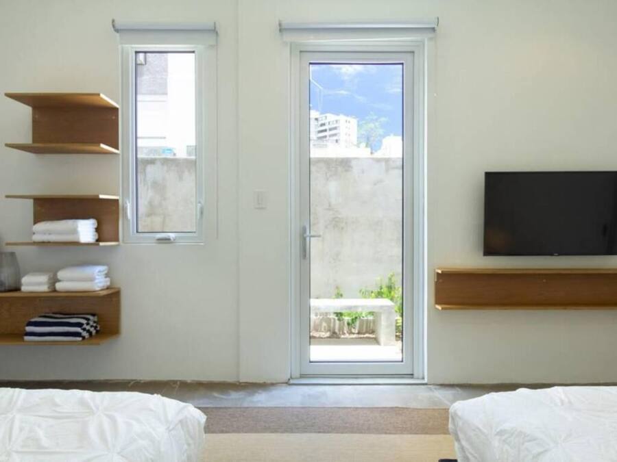 A bedroom with two beds, a TV, and a sliding glass door leading to an outdoor area.