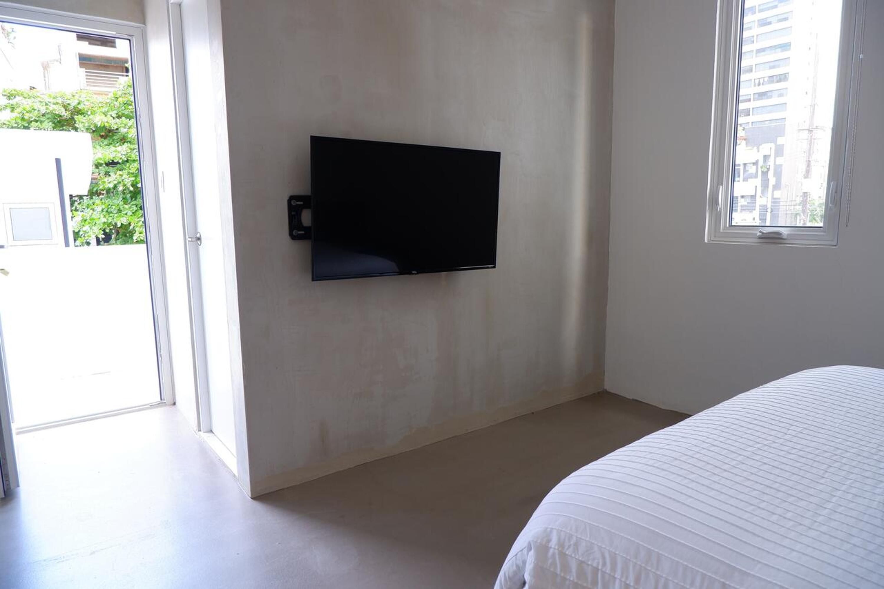 Quarto com cama, televisão de tela plana na parede e janela.