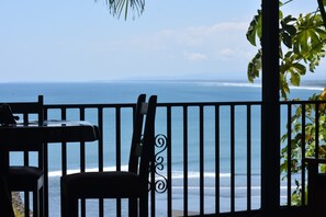 Un balcón con vistas al océano, una mesa y una silla.