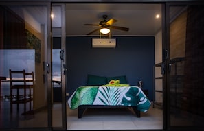 A bedroom with a bed, a ceiling fan, and a window.