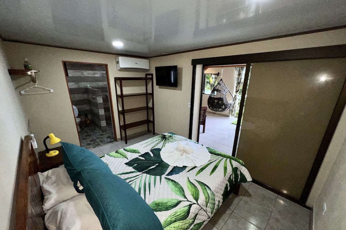 Une chambre à coucher comprenant un lit, un fauteuil suspendu, une armoire et un appareil de climatisation.