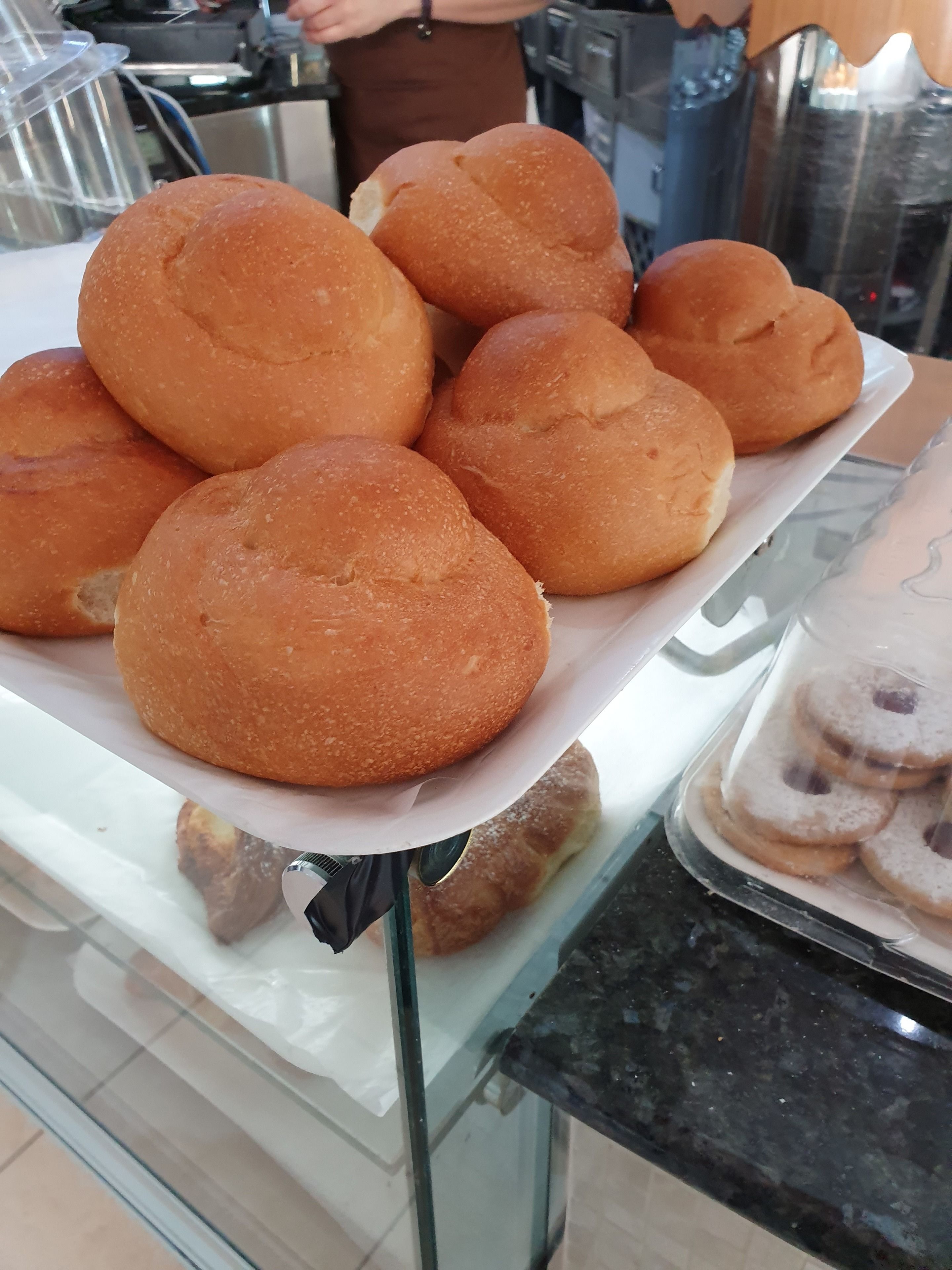 A tray of freshly baked rolls on a glass counter.