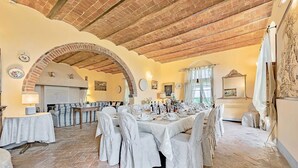 Une salle à manger avec un plafond en briques, des nappes blanches et une cheminée.