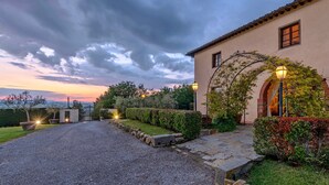 Une allée de gravier mène à un bâtiment, avec un chemin en pierre et un jardin bien entretenu.