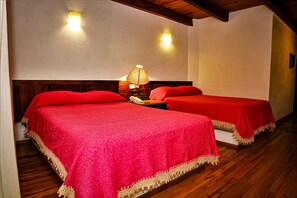A room with two beds, each with a red bedspread and a wooden headboard. There is a nightstand with a lamp between the beds. - Hotel Del Parque (Tequisquiapan)