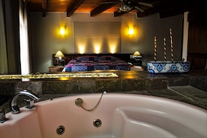 A bedroom with a large bed, bedside lamps, a nightstand, and a decorative blue vase with candles. - Hotel Del Parque (Tequisquiapan)