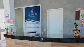 Una reception con un cartello per 'LA MARE Restaurant' e una porta chiusa sullo sfondo.