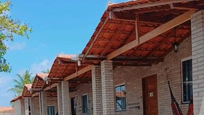 Una fila di edifici in mattoni con tetti in tegole rosse, scalini in pietra che conducono all'ingresso e amache appese alle pareti.