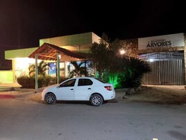 Un coche blanco estacionado frente a un edificio con un cartel que dice "RECANTO DAS ÁRVORES".