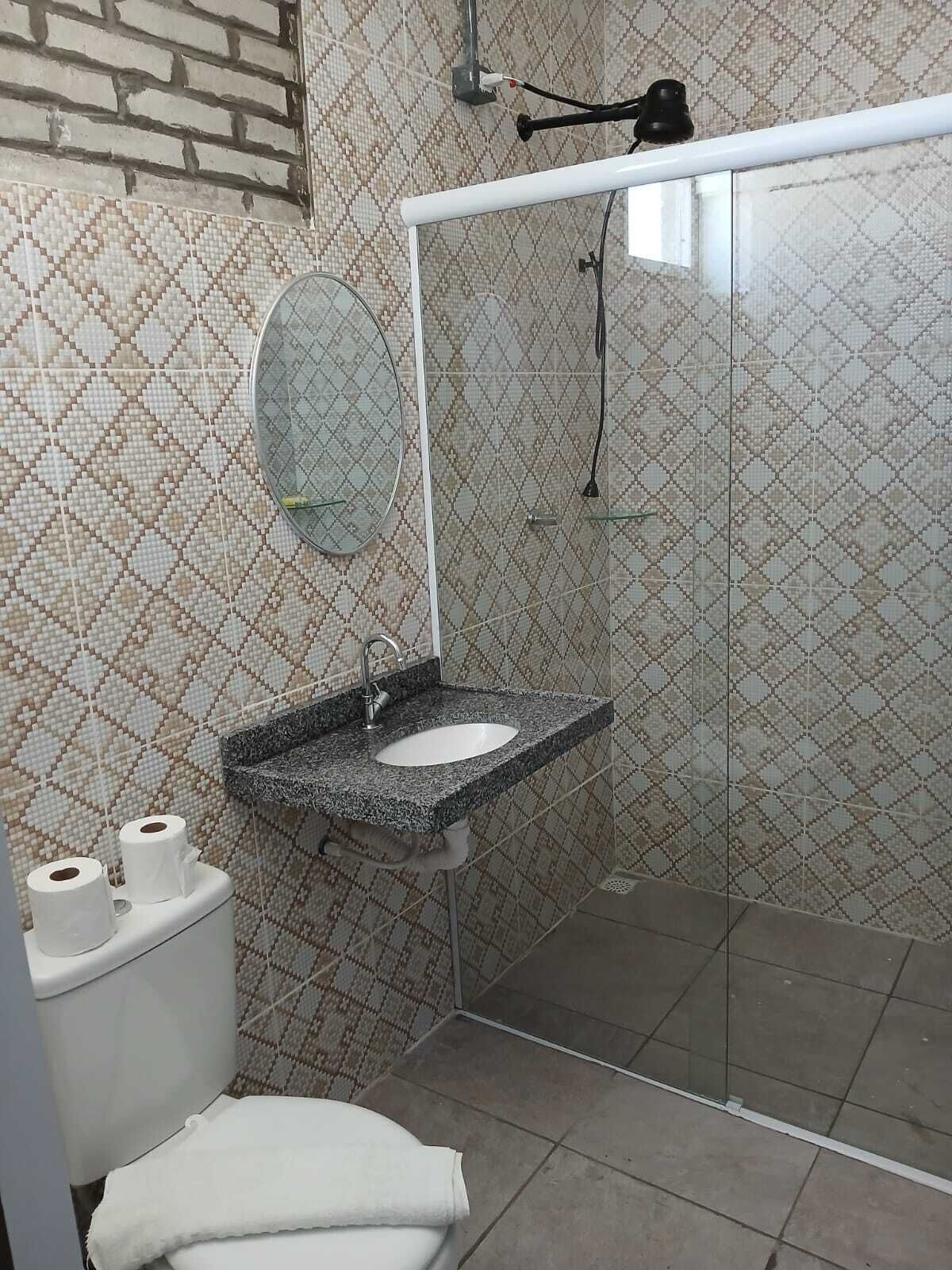 A bathroom with a shower, a sink, a toilet, and a mirror.