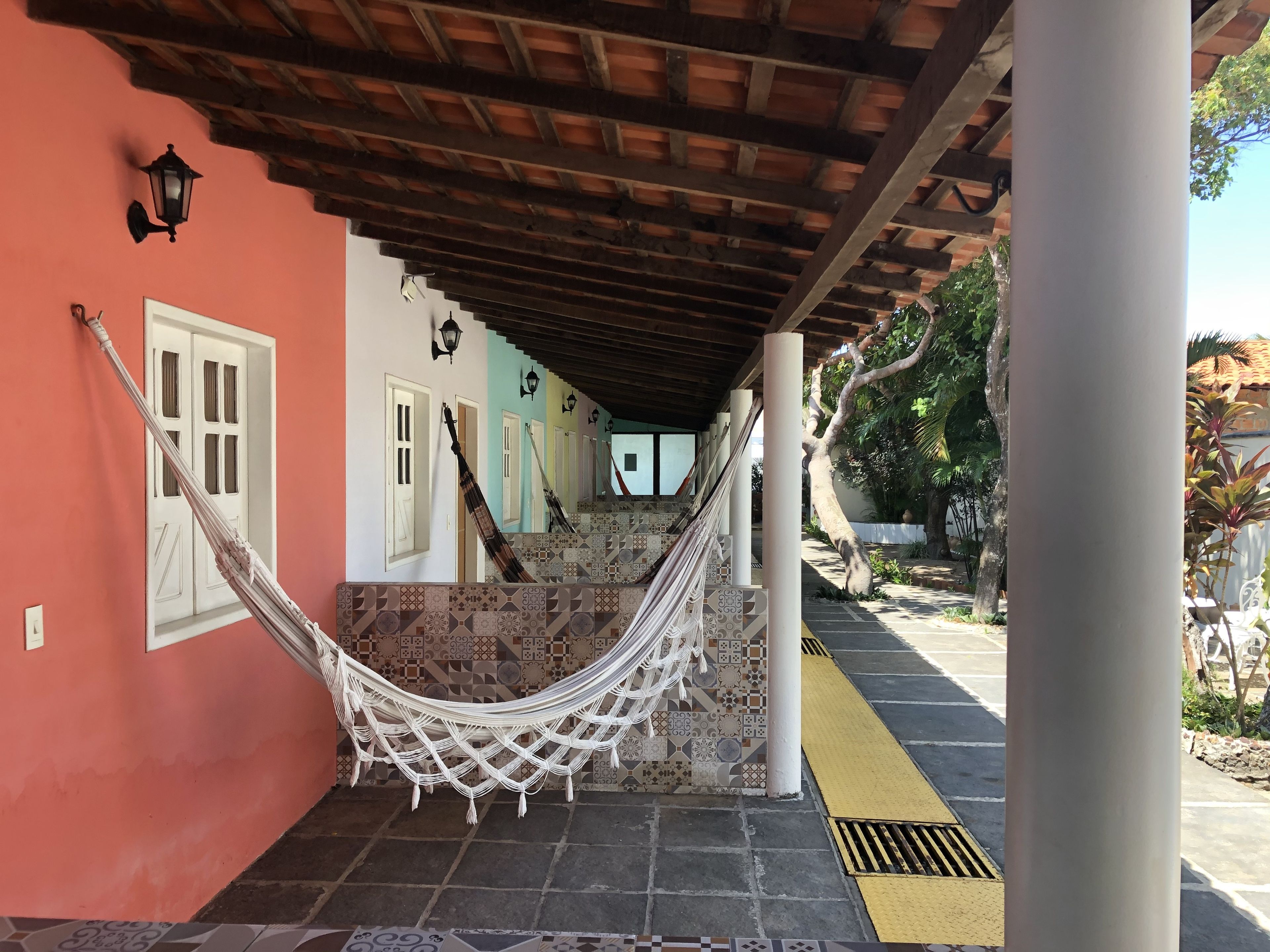 A hammock under a wooden pergola, a tiled staircase, and a pathway with tactile paving.