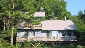 A cabin with a deck, surrounded by dense forest. -  Private Waterfront Setting on Lake Michigan (Shelby)