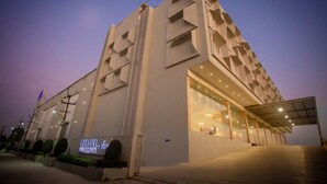 A modern building with a unique geometric facade, a prominent entrance with glass doors, and a sign indicating it is a hotel. - CITADEL Hotel By Vinnca (Hyderabad)