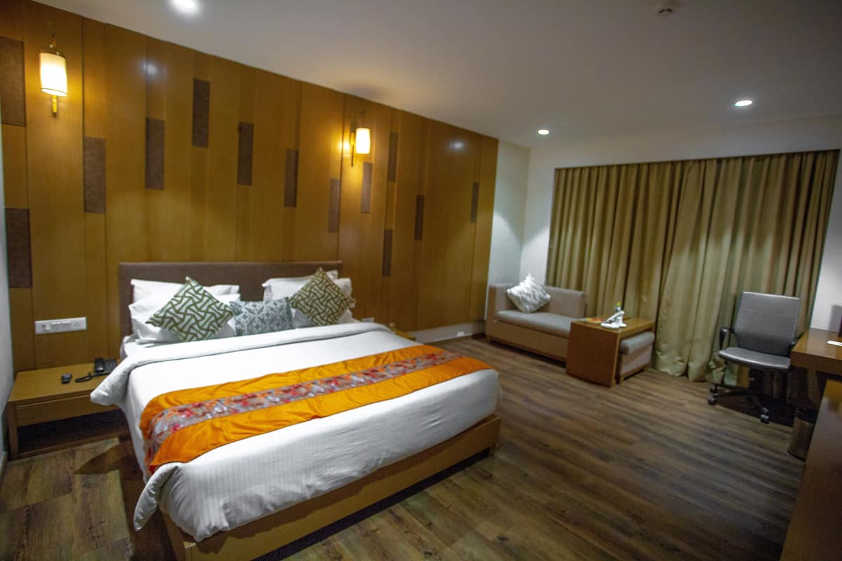 A hotel room with a large bed, a sofa, a desk, and a chair.