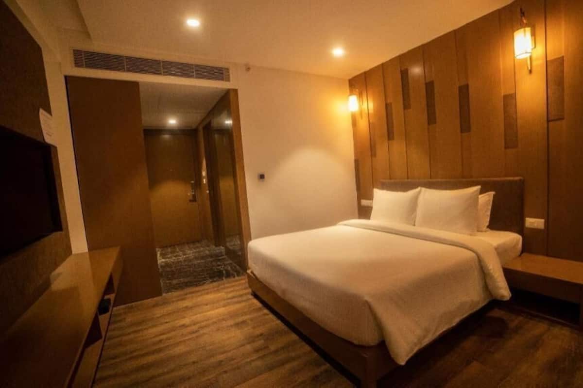 A hotel room with a bed, bedside table, and a wall-mounted light fixture.