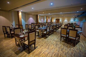 A conference room with multiple tables and chairs, arranged in rows. - CITADEL Hotel By Vinnca (Hyderabad)