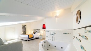 Un dormitorio moderno con una cama grande, una zona de estar y un baño con bañera.