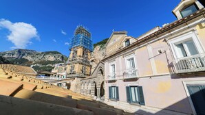 Un edificio histórico con un campanario en construcción, una escalera que lo lleva y vistas del paisaje montañoso circundante.