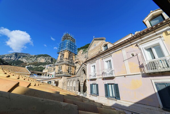 Un edificio histórico con un campanario en construcción, una escalera que lo lleva y vistas del paisaje montañoso circundante.
